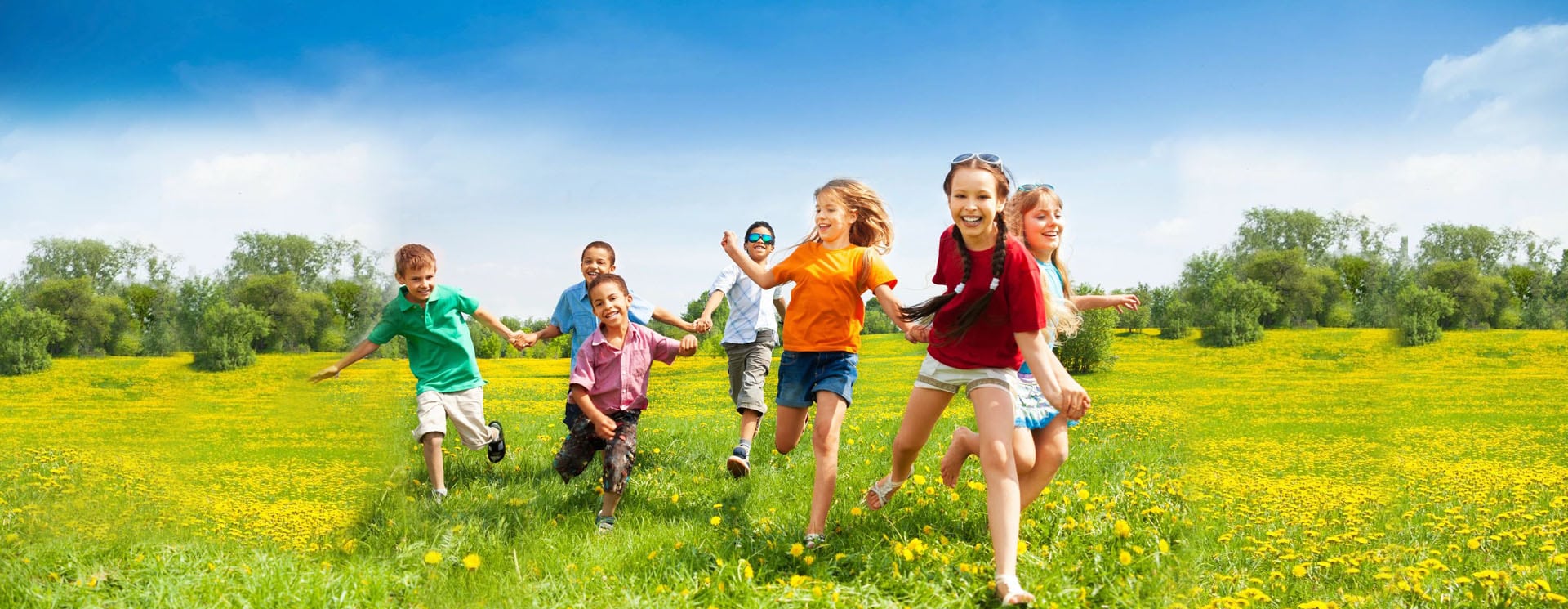 A group of children running in the grass.