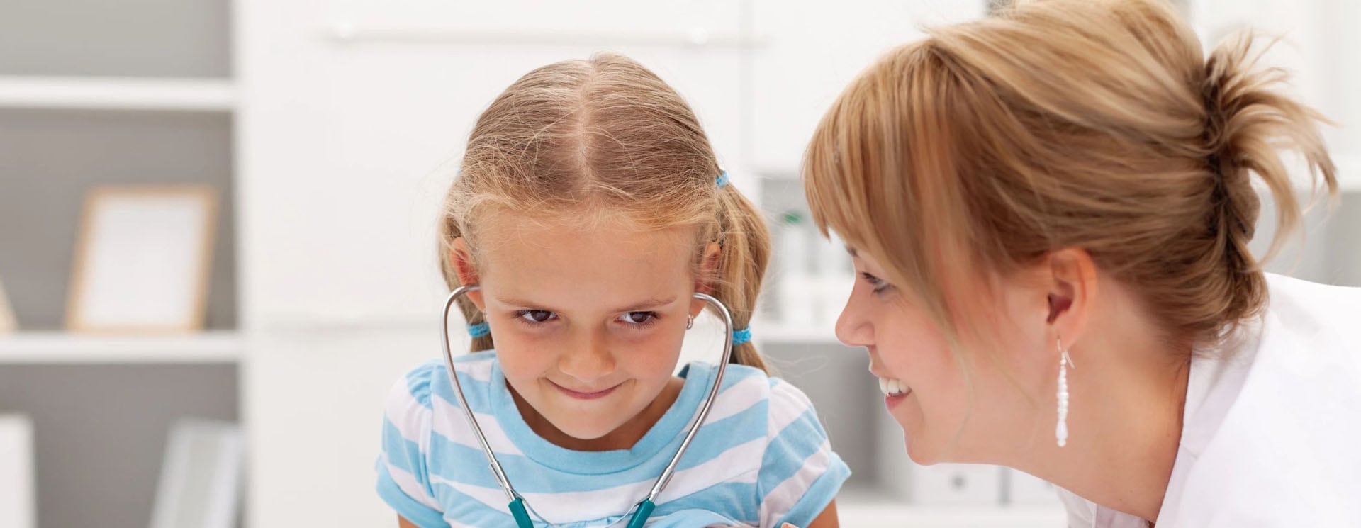 A little girl with her head examined by an adult.