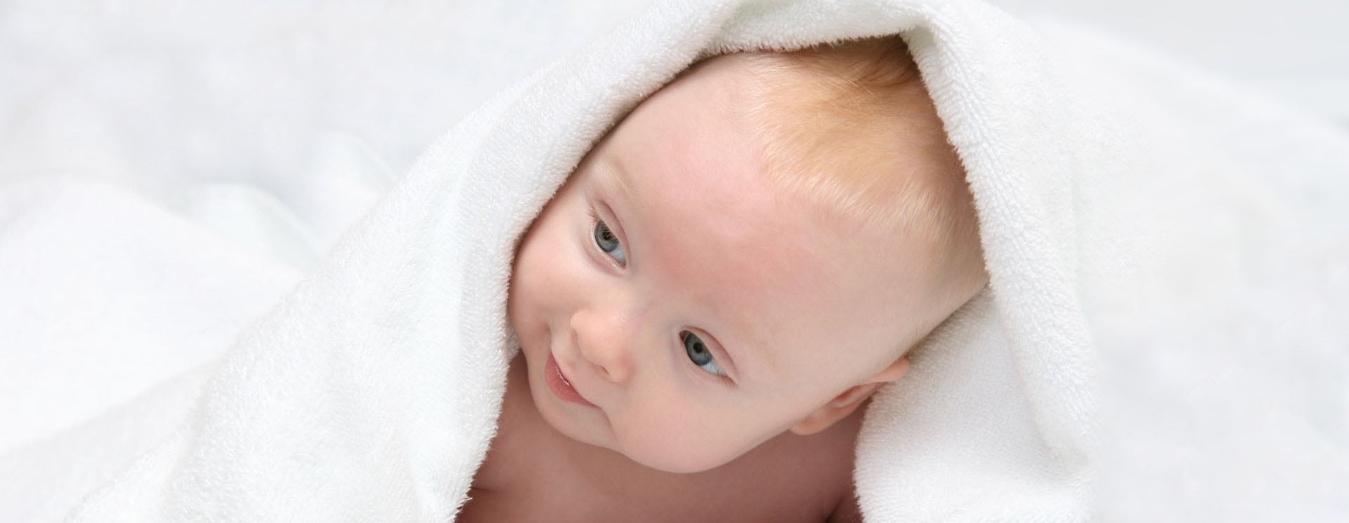 A baby wrapped in a blanket looking at the camera.