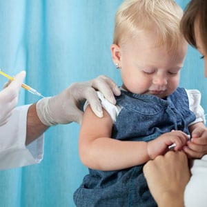 A woman is holding a baby and giving him an injection.