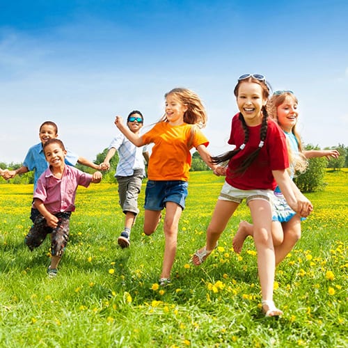 A group of kids running in the grass.