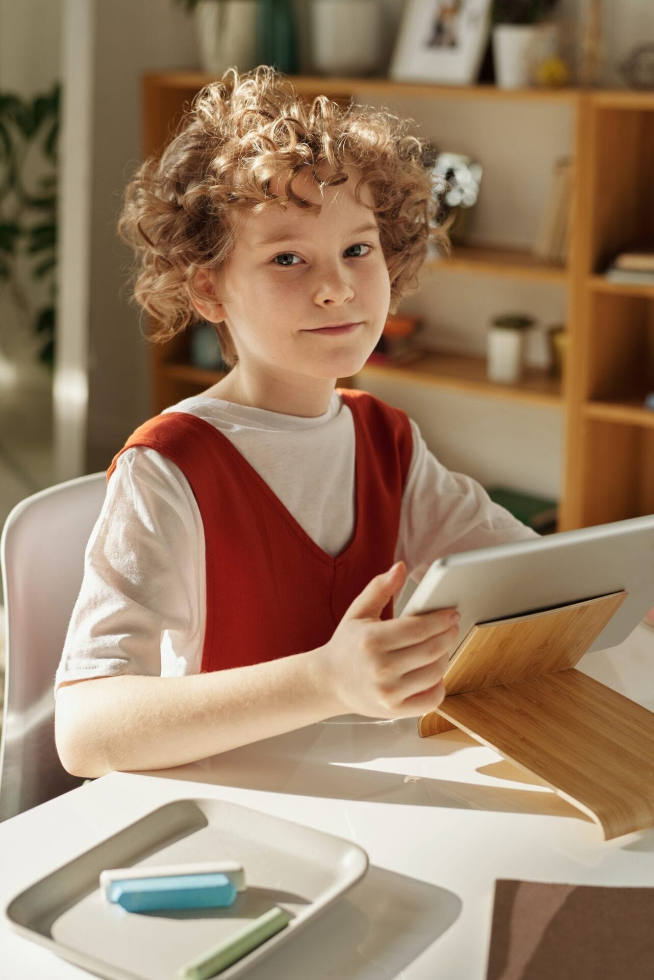 A young boy sitting at the table with an ipad.